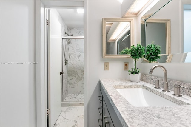 full bathroom featuring marble finish floor, a marble finish shower, and vanity