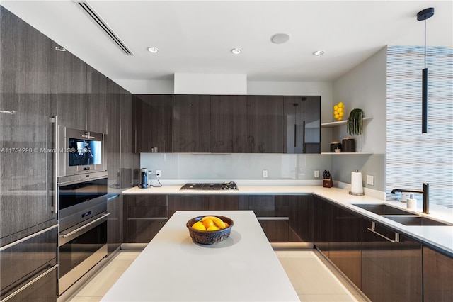 kitchen with stainless steel gas cooktop, light countertops, a sink, dark brown cabinetry, and modern cabinets