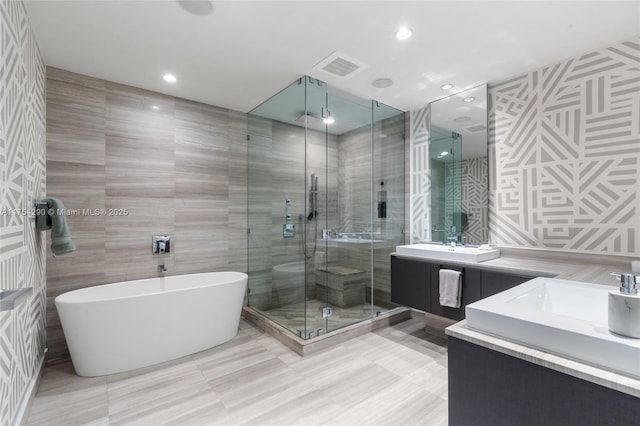 full bath with visible vents, vanity, a freestanding bath, tile walls, and a shower stall