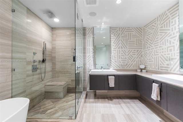 bathroom featuring double vanity, visible vents, a freestanding bath, a stall shower, and a sink