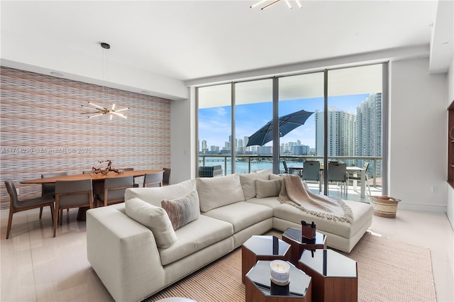 tiled living room featuring floor to ceiling windows, a city view, a notable chandelier, an accent wall, and baseboards