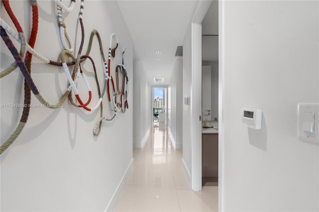 hall featuring light tile patterned floors, visible vents, and baseboards