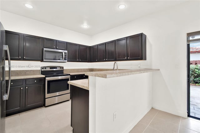 kitchen featuring light tile patterned floors, stainless steel appliances, recessed lighting, light countertops, and a peninsula