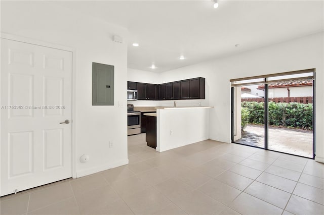 kitchen featuring light tile patterned floors, a peninsula, light countertops, appliances with stainless steel finishes, and electric panel