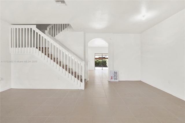 stairs featuring tile patterned flooring, visible vents, and arched walkways