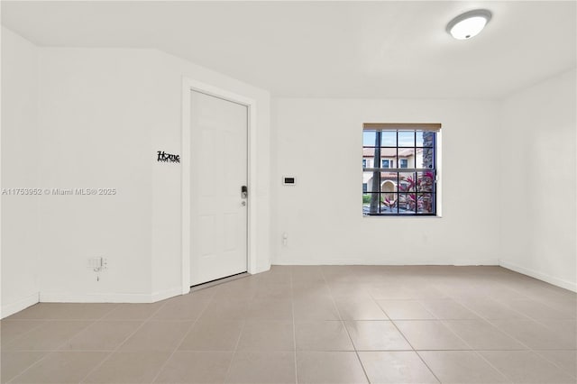 unfurnished room with light tile patterned floors and baseboards