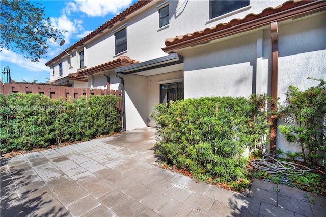 view of side of home featuring a patio, a tile roof, and stucco siding