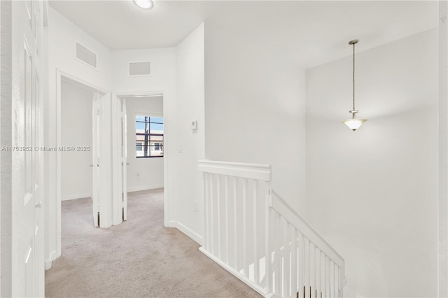 hallway with visible vents, carpet floors, an upstairs landing, and baseboards