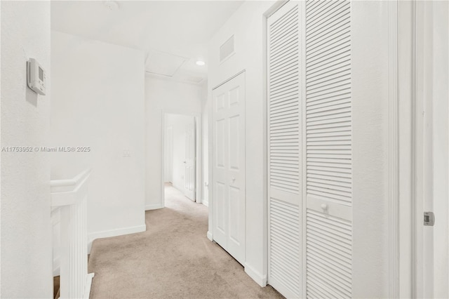 hall featuring light carpet, visible vents, attic access, and baseboards