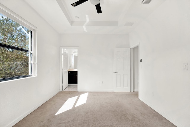 unfurnished bedroom featuring a raised ceiling, light carpet, connected bathroom, ceiling fan, and baseboards