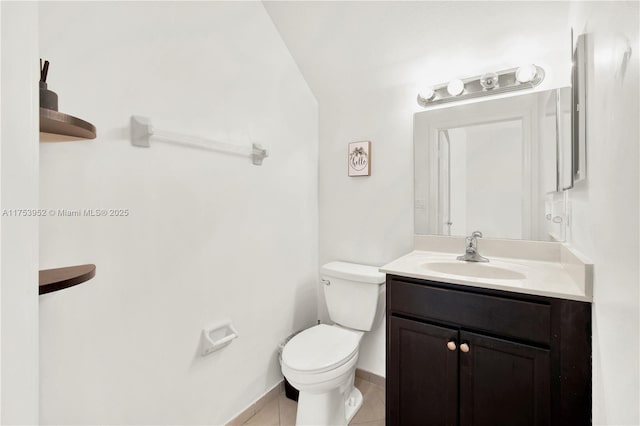 half bath with toilet, tile patterned flooring, and vanity