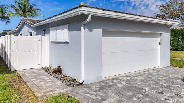 garage with a gate, fence, and decorative driveway