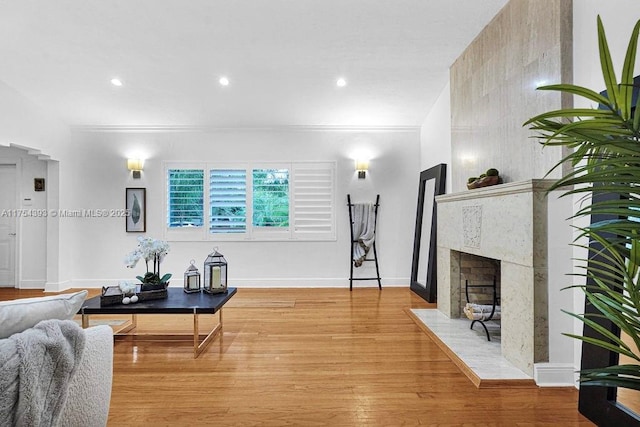 living area featuring a fireplace, recessed lighting, ornamental molding, wood finished floors, and baseboards