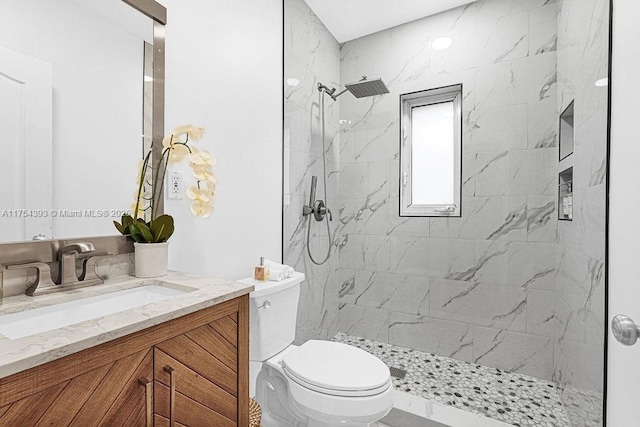 bathroom with toilet, a marble finish shower, and vanity