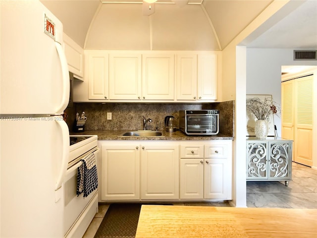 kitchen with white appliances, a sink, visible vents, vaulted ceiling, and tasteful backsplash