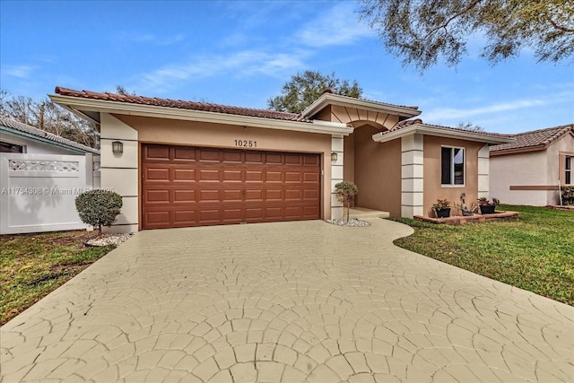 view of front of house with a garage, a tile roof, driveway, stucco siding, and a front yard