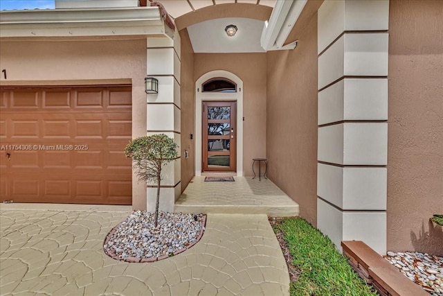 view of exterior entry featuring a garage and stucco siding