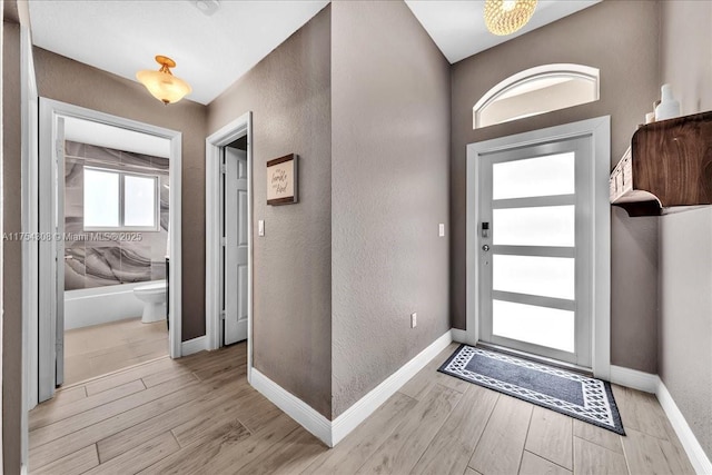 entryway featuring light wood finished floors, baseboards, and a textured wall