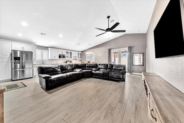 living area with vaulted ceiling, ceiling fan, light wood finished floors, and visible vents