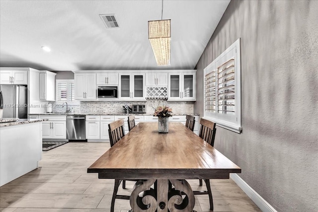 dining room featuring a textured wall, light wood-type flooring, visible vents, and baseboards