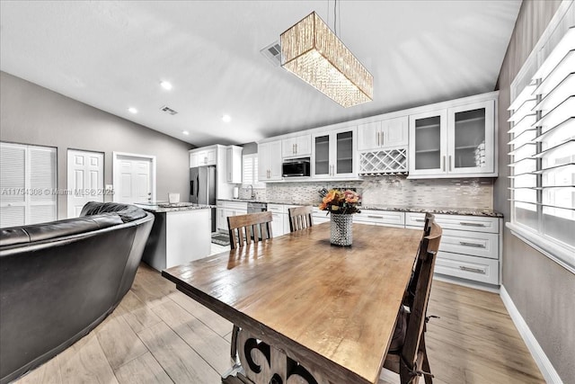 dining room with lofted ceiling, recessed lighting, visible vents, light wood-style flooring, and baseboards