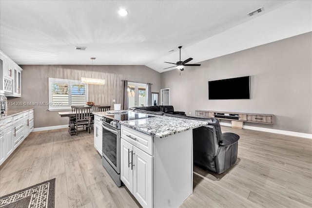 kitchen with a center island, lofted ceiling, visible vents, electric range, and white cabinetry