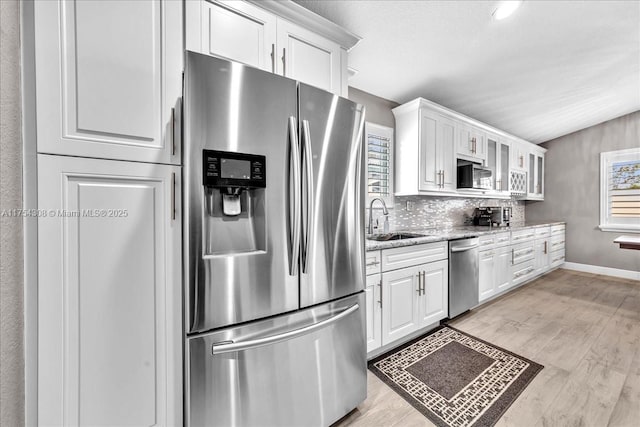 kitchen featuring stainless steel appliances, a sink, white cabinetry, and light wood-style floors