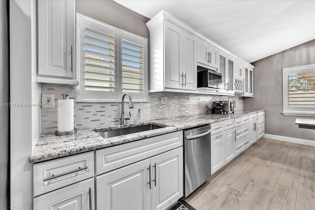 kitchen featuring appliances with stainless steel finishes, a sink, white cabinetry, and decorative backsplash