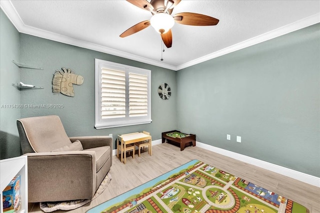 recreation room featuring crown molding, baseboards, ceiling fan, and wood finished floors