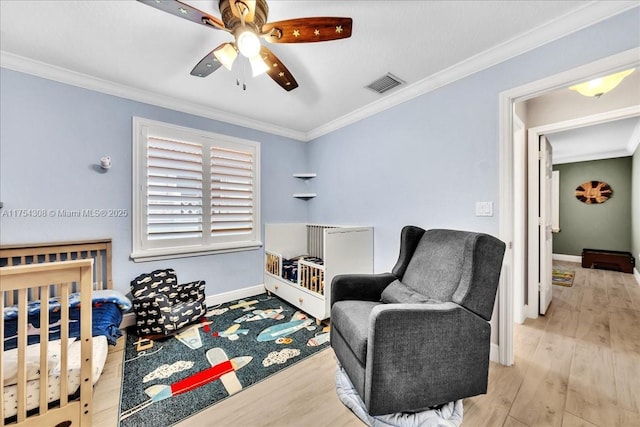 bedroom featuring ornamental molding, wood finished floors, visible vents, and baseboards