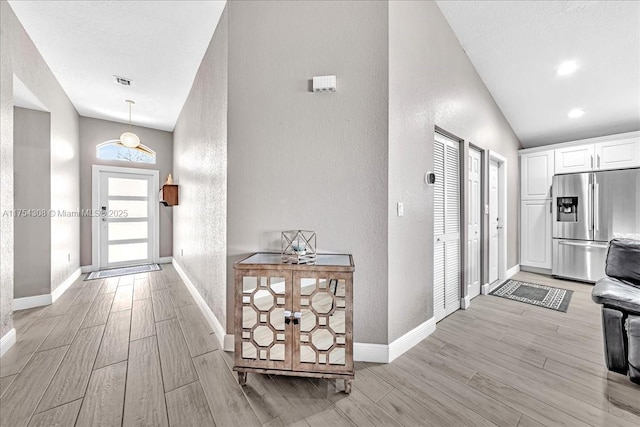 foyer entrance with wood tiled floor, visible vents, baseboards, and a textured wall