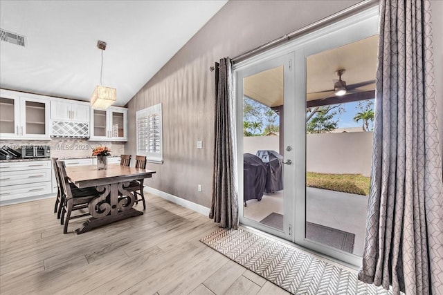 dining room featuring light wood finished floors, baseboards, visible vents, a ceiling fan, and vaulted ceiling