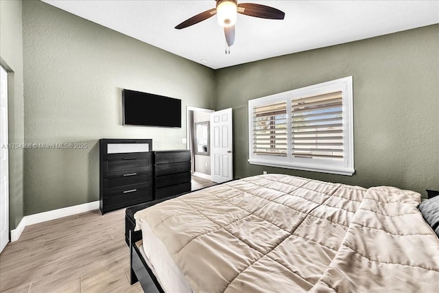 bedroom featuring a textured wall, wood finished floors, a ceiling fan, and baseboards