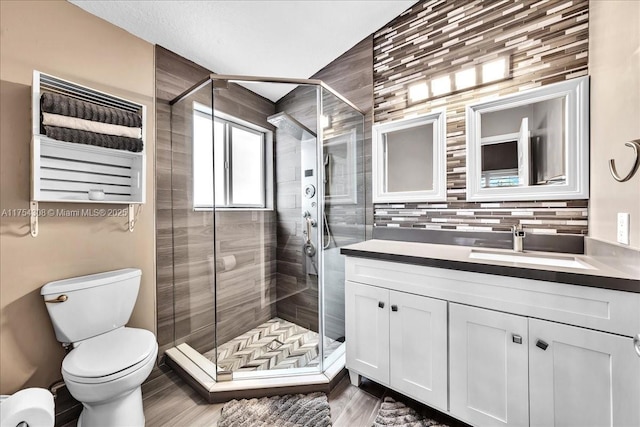 bathroom with toilet, a shower stall, wood finished floors, and vanity