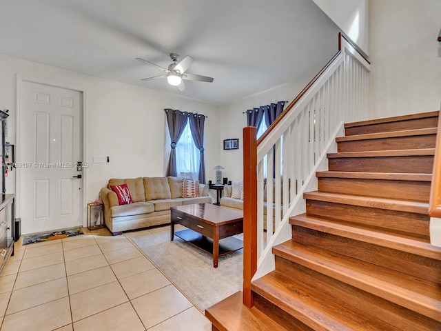 living area featuring light tile patterned floors, stairs, and a ceiling fan