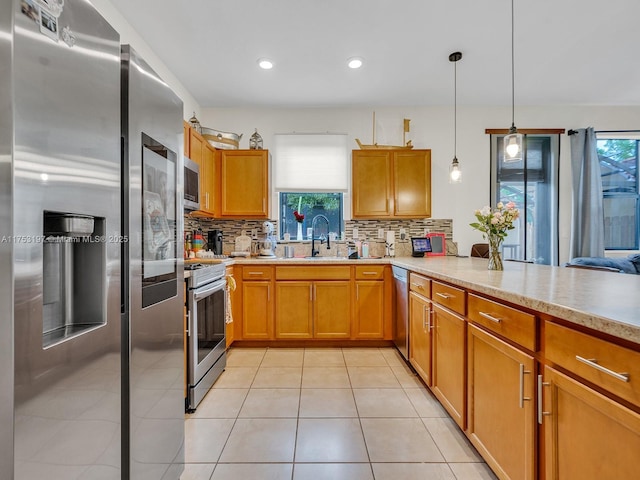 kitchen featuring light tile patterned floors, a sink, light countertops, appliances with stainless steel finishes, and a wealth of natural light