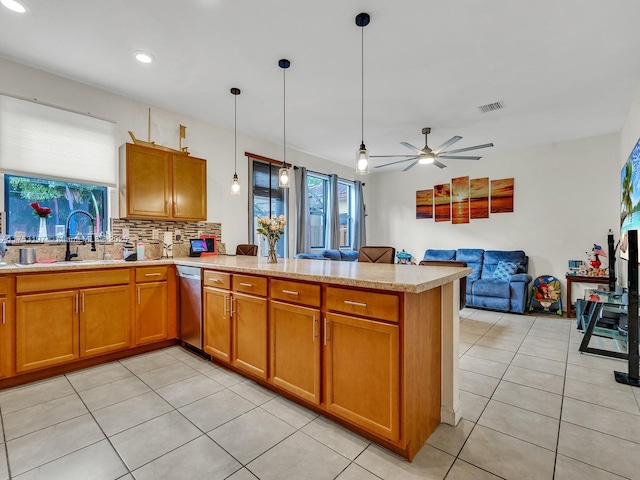 kitchen featuring brown cabinets, light countertops, visible vents, a sink, and a peninsula