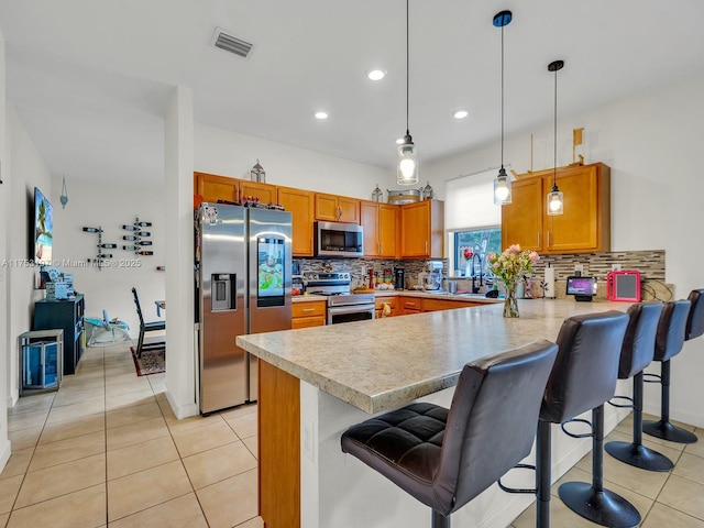 kitchen featuring stainless steel appliances, light countertops, visible vents, and a peninsula