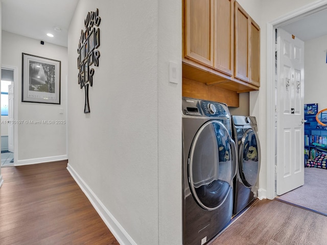 washroom with cabinet space, baseboards, dark wood finished floors, and washing machine and clothes dryer