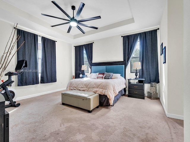 carpeted bedroom with baseboards, multiple windows, and a tray ceiling