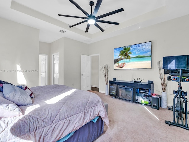 bedroom featuring a ceiling fan, a raised ceiling, visible vents, and carpet flooring