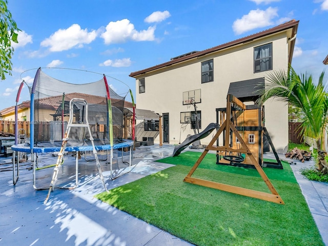 view of jungle gym with a trampoline, fence, and a lawn