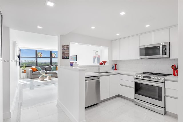 kitchen with decorative backsplash, appliances with stainless steel finishes, white cabinets, and a sink