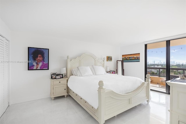 bedroom with light tile patterned floors, baseboards, access to exterior, expansive windows, and a view of city