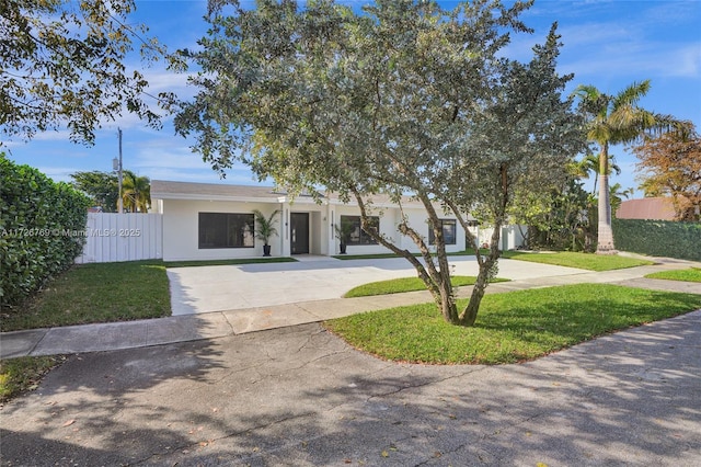 view of front of property featuring driveway, fence, a front lawn, and stucco siding