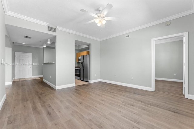 empty room featuring a ceiling fan, visible vents, light wood-style flooring, and baseboards