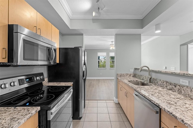 kitchen featuring light tile patterned floors, a raised ceiling, stainless steel appliances, crown molding, and a sink