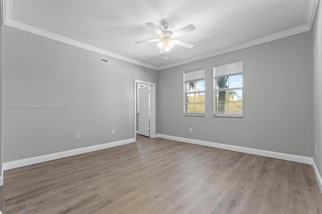 spare room with ornamental molding, visible vents, ceiling fan, and baseboards