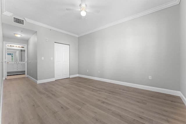 unfurnished bedroom featuring wood finished floors, visible vents, baseboards, ornamental molding, and a closet