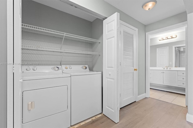 laundry room with baseboards, laundry area, light wood-style flooring, and washer and dryer